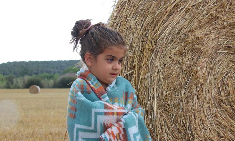 Girl covered with a blanket in a field