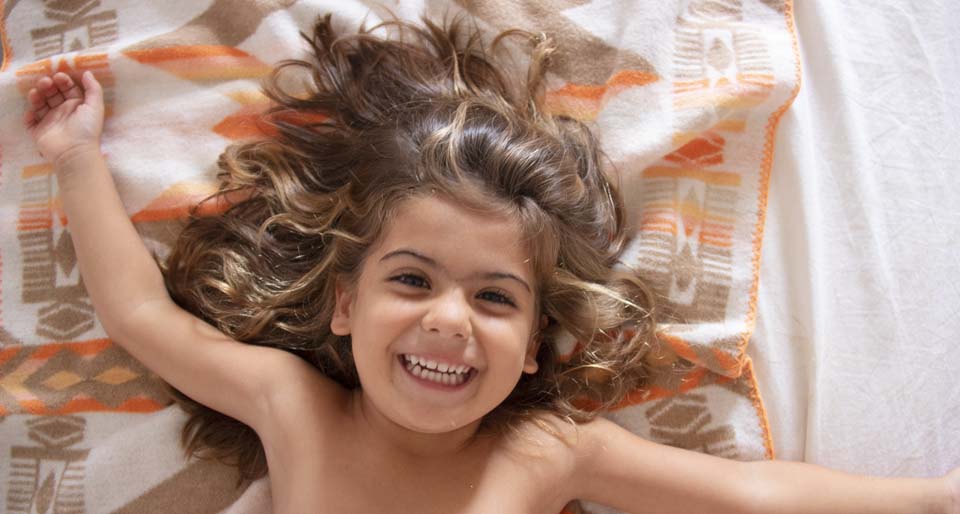 Laughing girl lying on a baby blanket